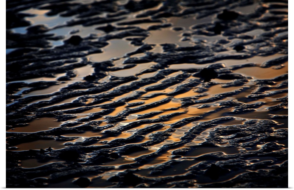 An abstracted sand pattern image reflecting golden light with deep purple and blue tones.