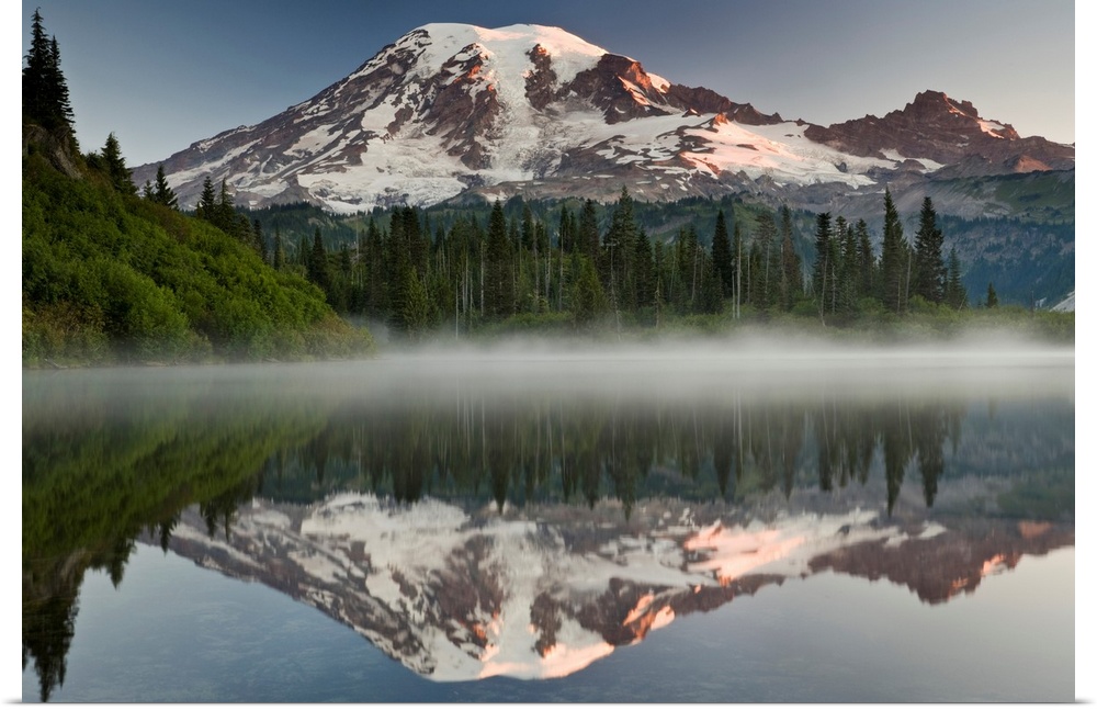 Big photograph shows the great size of snow-covered Mount Rainier in the background reflecting over one of the many lakes ...