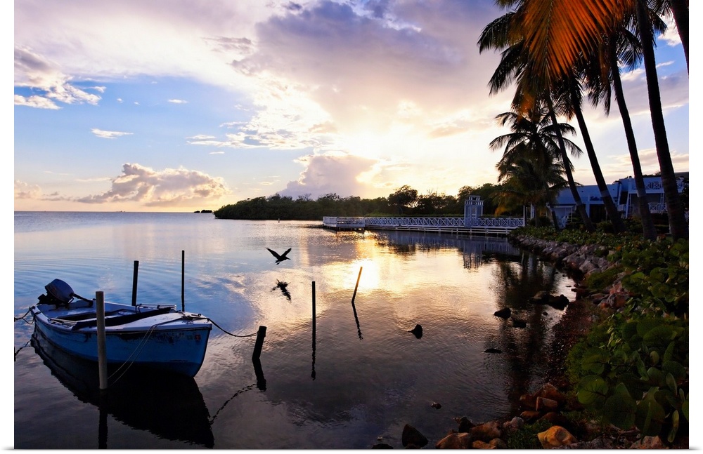 Large landscape photograph of the sun setting over the coast near a fishing village in La Parguera, Puerto Rico.  Palm tre...