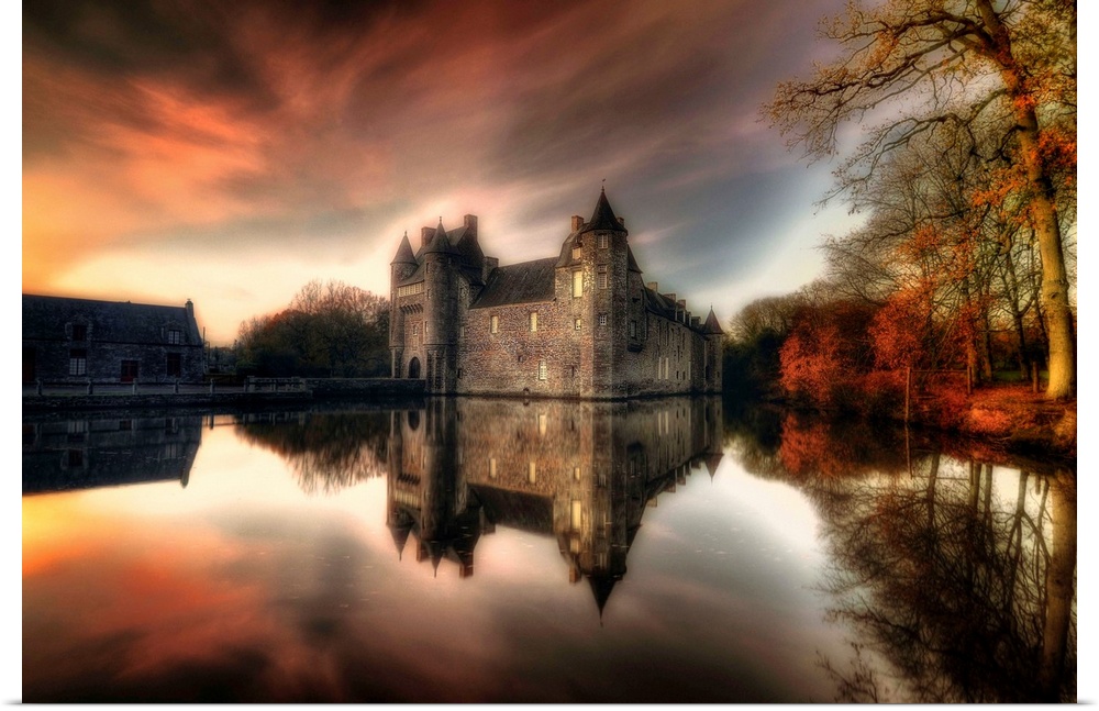 A large castle sits right on the water and reflects perfectly just below. The sunset glows in the sky and reflects into th...