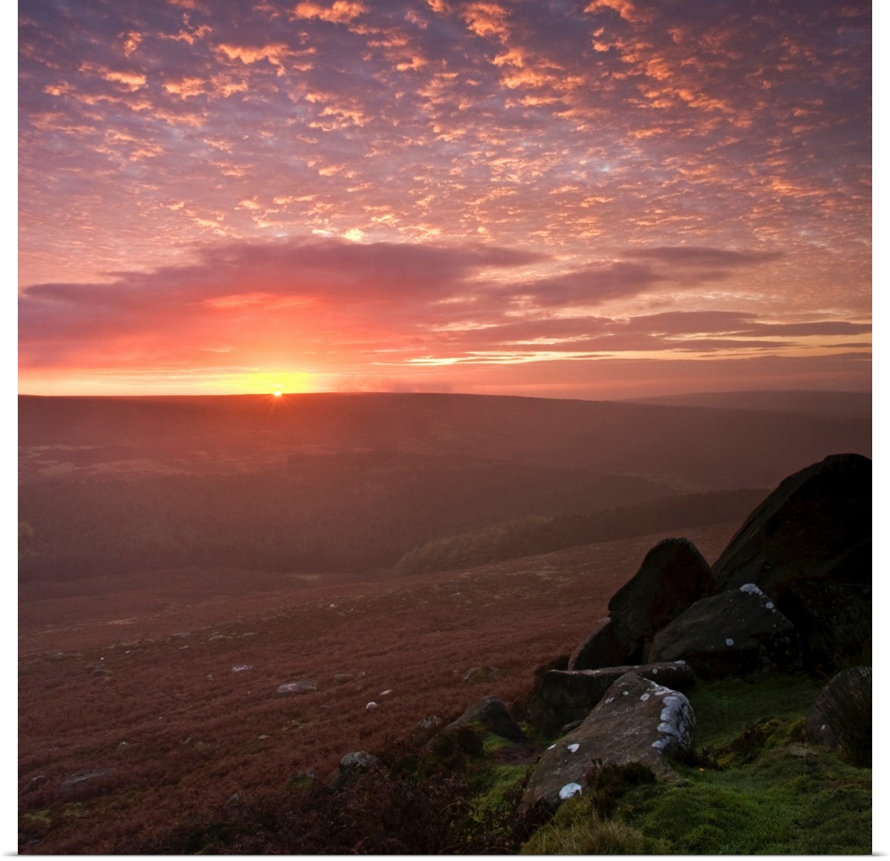 An optimistic golden yellow sunrise in the English Peak District National Park with fluffy clouds.