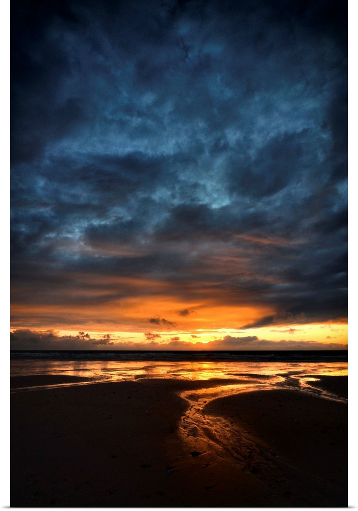 Sunrise with orange and blue colors on a sand beach in France, vertical view.