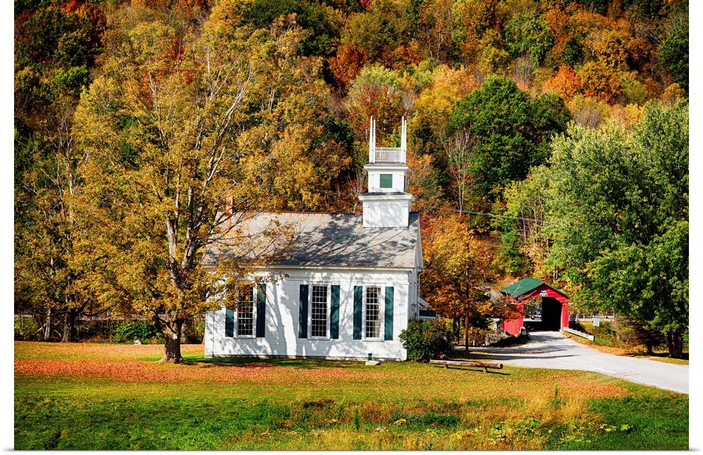 A Baptist church in a forest with fall foliage and a covered bridge visible in the distance.
