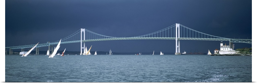 Stark white suspension bridge and boats on the water contrasted against a darkening sky, sailing away from the oncoming sq...