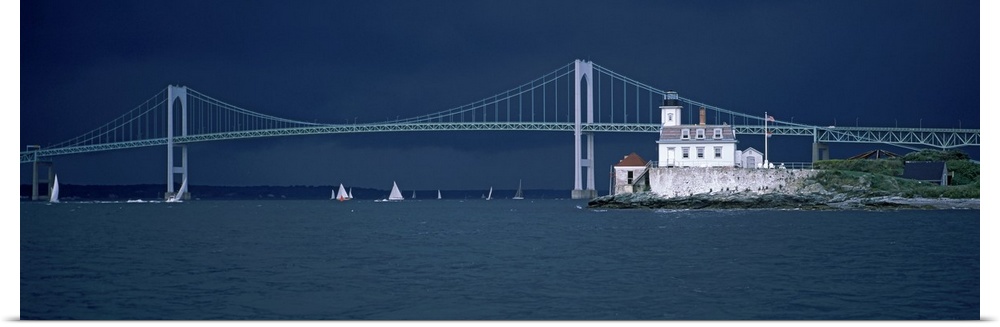 A storm approaches sailboats racing past Rose Island lighthouse and the Newport Bridge in Narragansett Bay, Newport, Rhode...