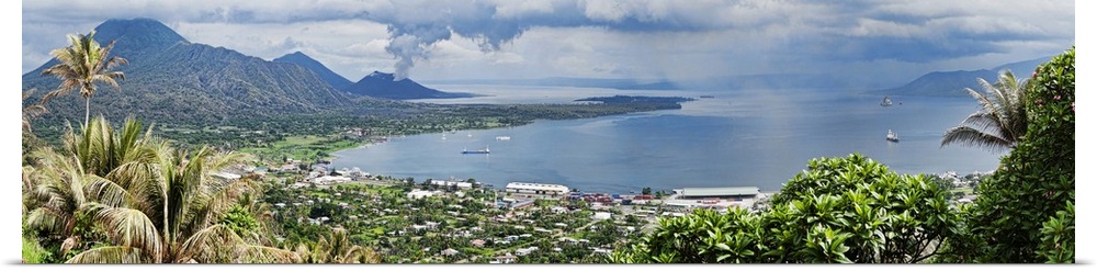 High angle view of a town on the coast with volcano in the background, Tavurvur, Rabaul, East New Britain, Papua New Guinea.