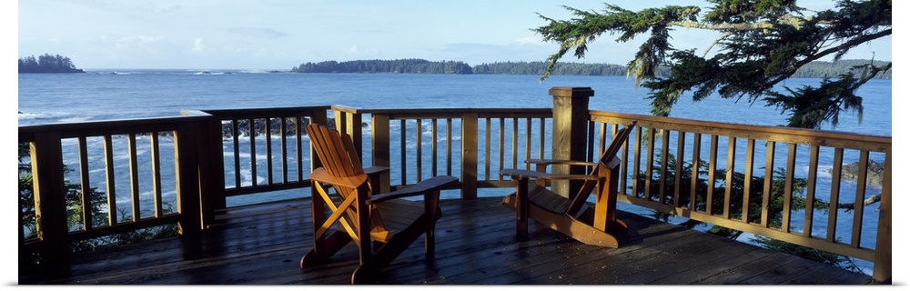 Two chairs sit on a raised deck overlooking a large body of water.