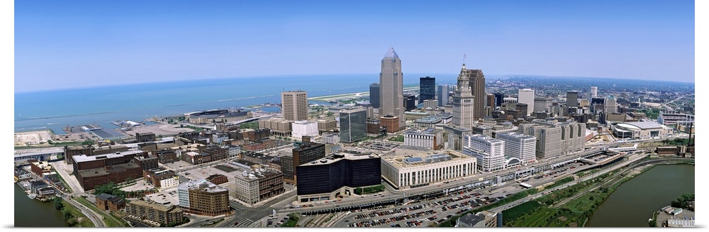 Horizontal, aerial photograph of the Cleveland Ohio skyline beneath a blue sky.