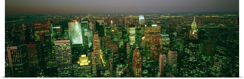 High angle view looking down at New York City and all the tall buildings glowing windows in the early night sky.