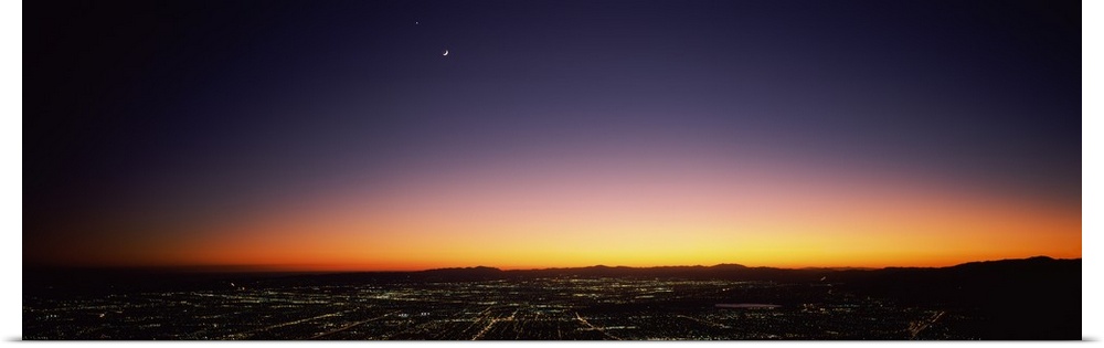 An aerial photograph taken of Los Angeles at night with the sun just setting below the horizon.
