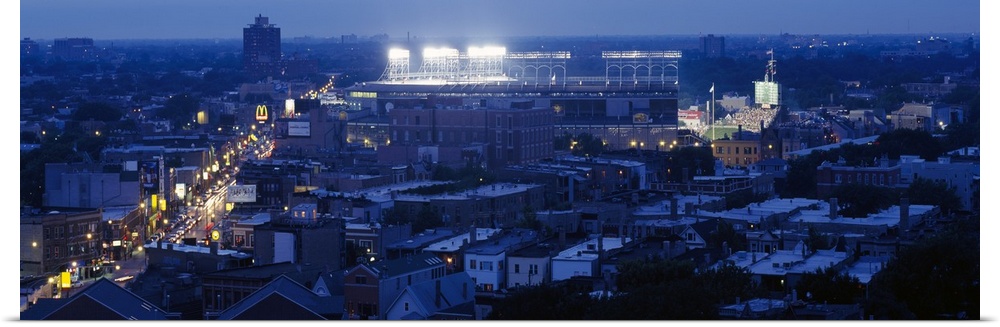This high angle photograph is taken from a distance but focused on the Chicago Cubs stadium as it's illuminated for a nigh...