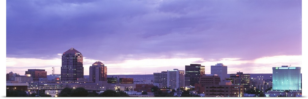 Panoramic photograph on a big canvas of the Albuquerque skyline with lit skyscrapers at night, beneath a cloudy sky in New...