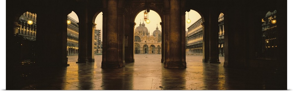 Panoramic photograph taken of St. Marks Square in Venice looking through stone arches and into the square.