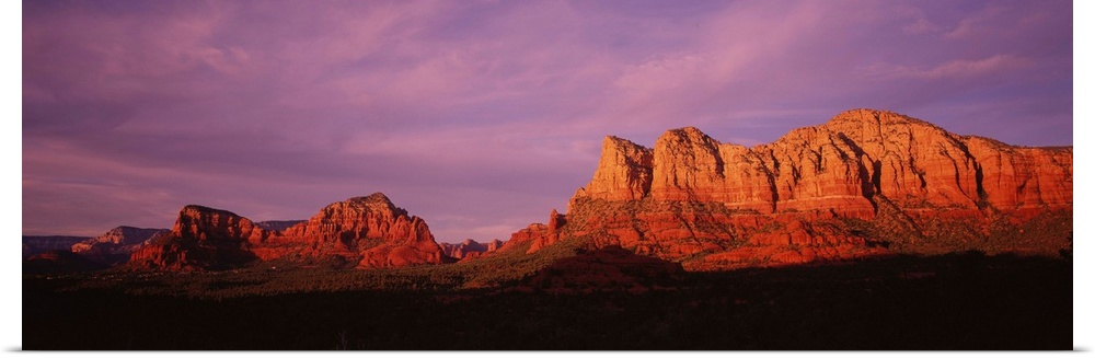 This photograph is a panoramic wall hanging that captures the fading light illuminating the desert cliffs.