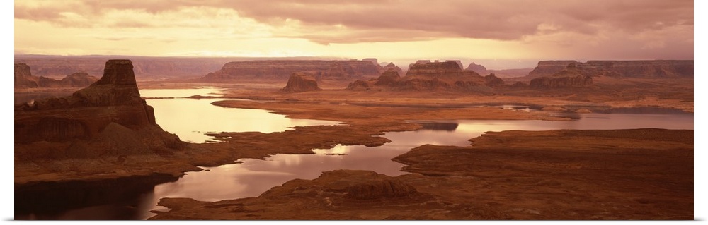 Large panoramic photograph of the sun beginning to rise over Lake Powell and the red rock desert mountains
