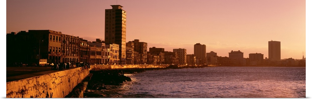 This wide angle picture is taken of buildings lining a body of water in Havana Cuba during sun down.