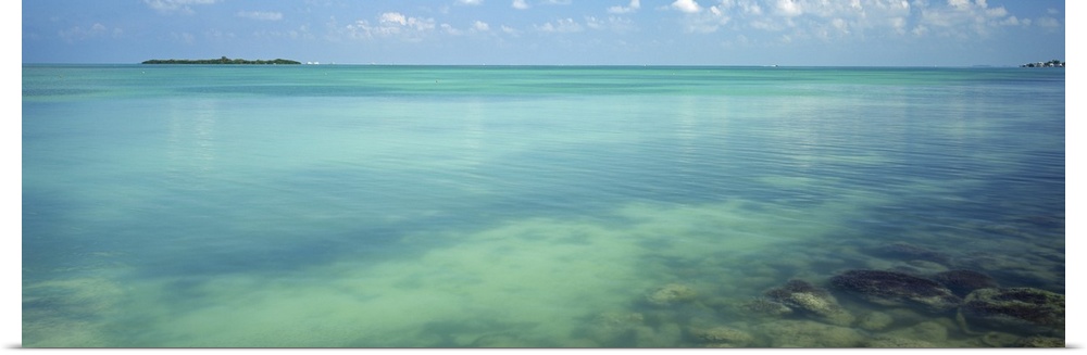 Still, clear waters in a tropical sea in this panoramic seascape photograph.
