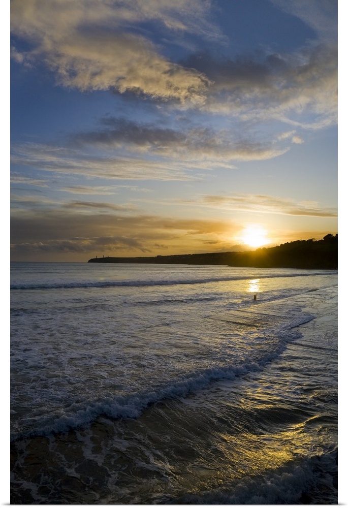 This is a photograph of a sunset off the coast of Ireland with small waves crashing onto the beach.