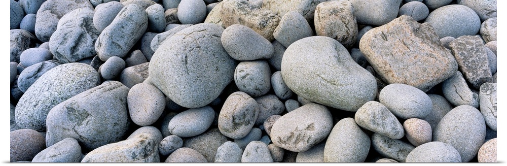 Up-close panoramic photograph of seaside pebbles and rocks.