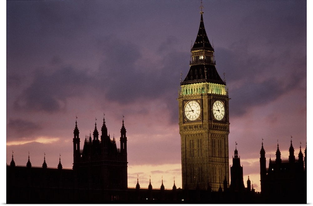 A lit up Big Ben clock exends in to the dusk London sky rising high above the spires of Parlament buildings in the backgro...