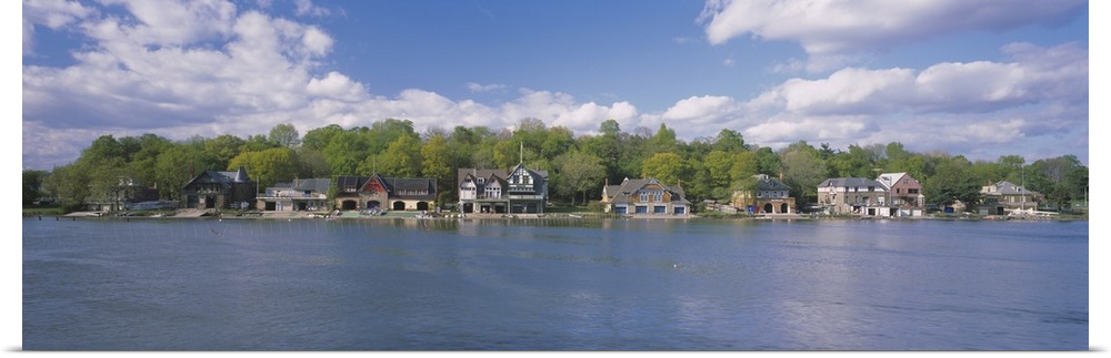 Panoramic photo of boathouses lining a waterfront.
