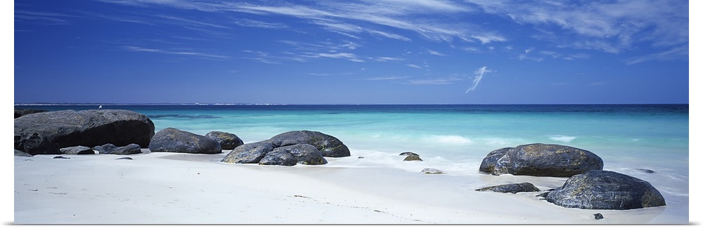 Wide angle photograph on a large canvas of big rocks on a white sand beach near the crystal blue waters of Flinders Bay in...