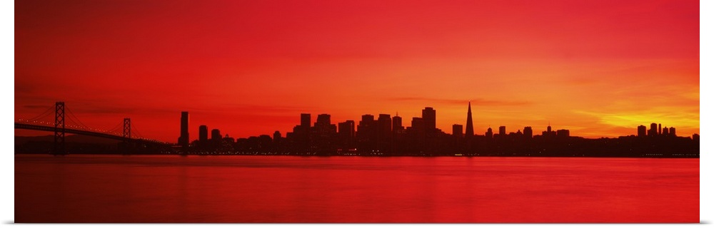 Panoramic photograph of iconic suspension overpass and skyline at waterfront at sunset.