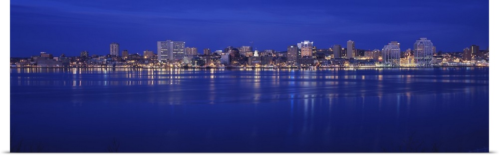 Large panoramic print of buildings lit up along a water front at night in Canada.