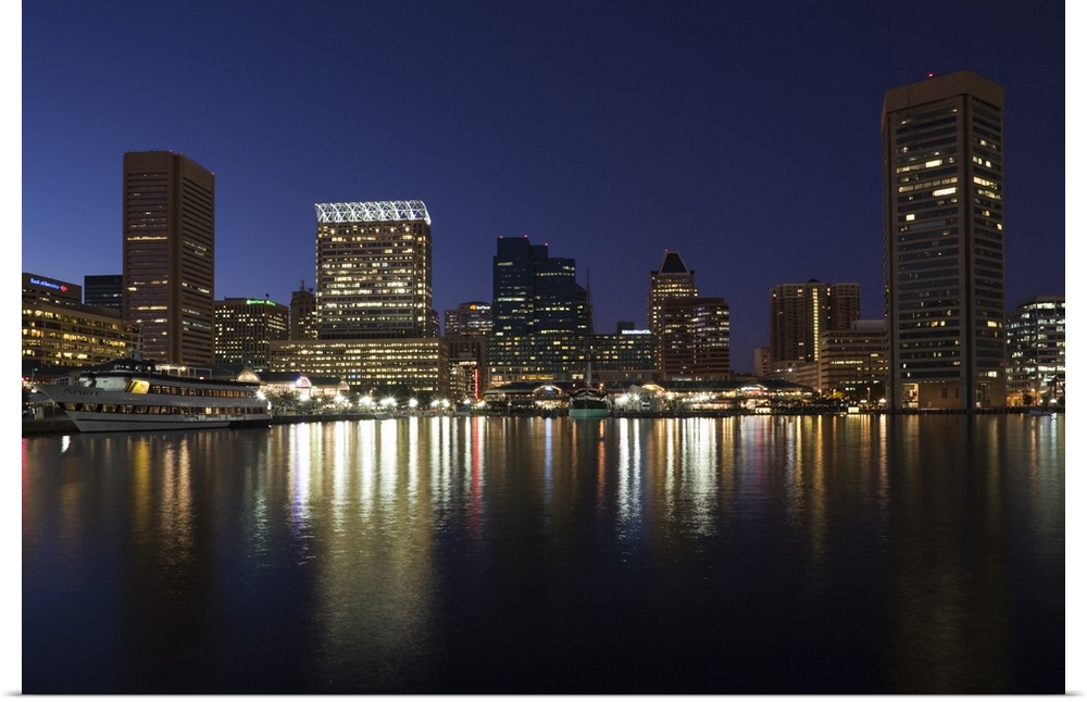 City skyscrapers reflecting their lights onto the water of the Inner Harbor in Baltimore, Maryland.