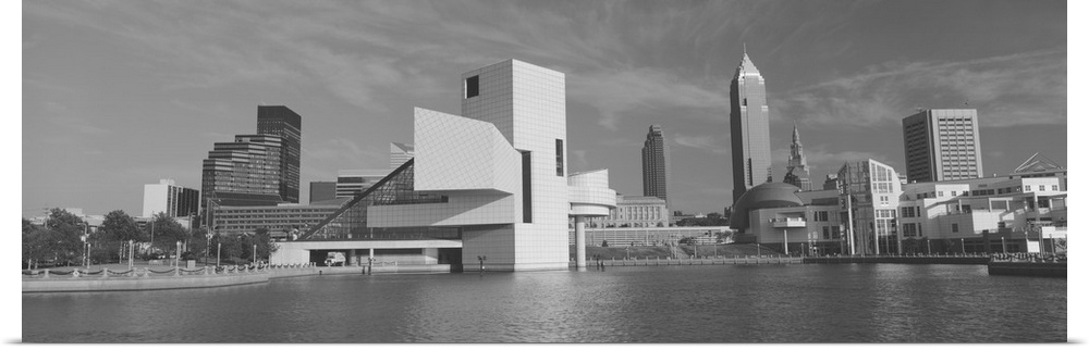 A black and white panoramic photograph taken of buildings in Cleveland sitting on water with the rock and roll hall of fam...