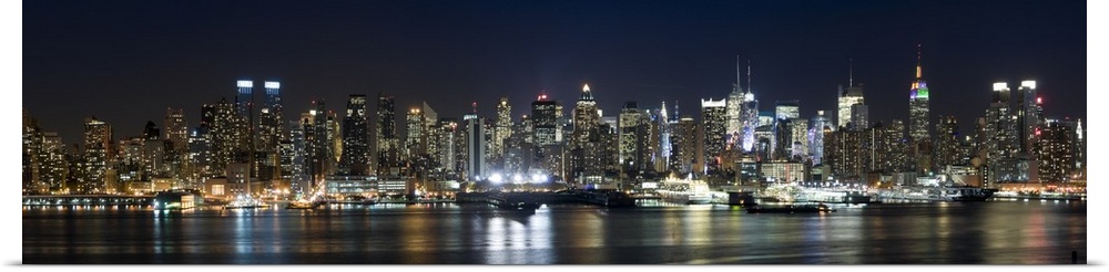 Panoramic photograph of city skyline at dusk with the building lights reflected in the waterfront.