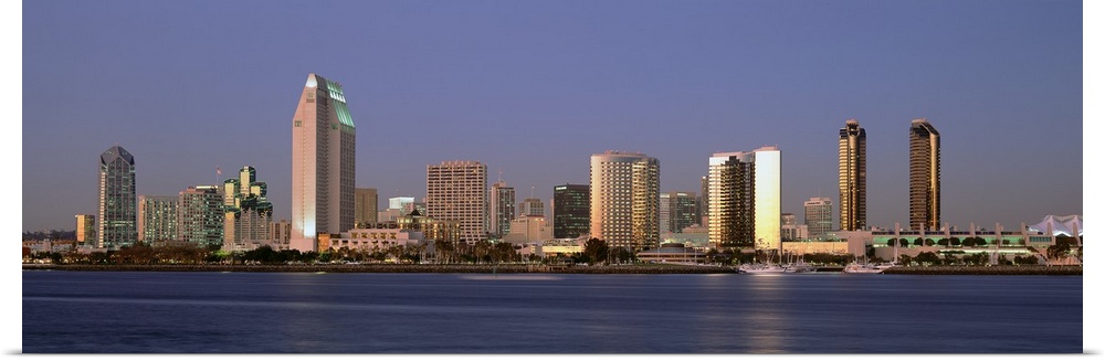 Wide angle photograph of the San Diego skyline over the water, beneath a blue sky during the day.
