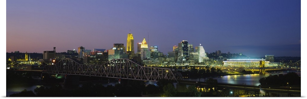 The Cincinnati skyline is photographed in panoramic view and illuminated under a night sky.