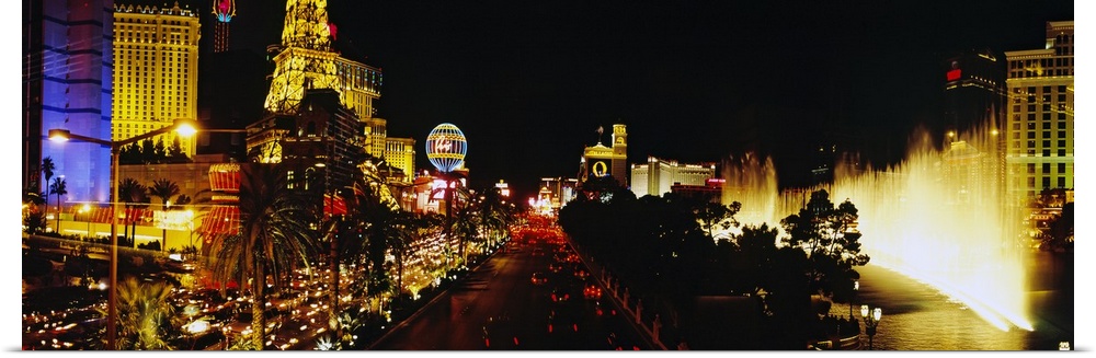 Panoramic photograph displays the brightly lit strip of Las Vegas, Nevada filled with hotels, casinos and a fountain in th...