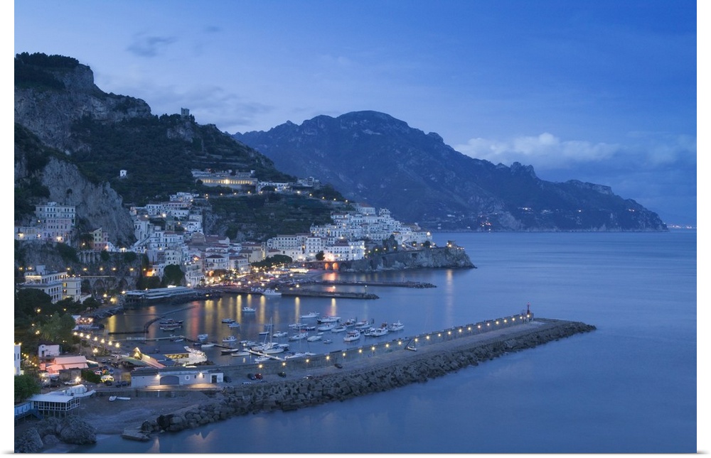 Big, landscape photograph of lit buildings along a hillside on the Amalfi Coast, in Campania, Italy, at dusk.