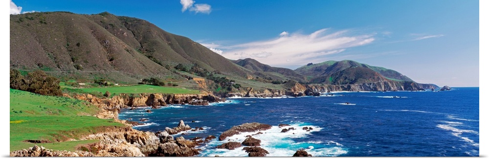 Wide angle photograph of the coastline in Big Sure, California.  Hills jutting into the blue waters of the Pacific Ocean.