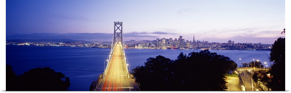 San Francisco Bridge light up at night over the Bay with views of downtown skyline.