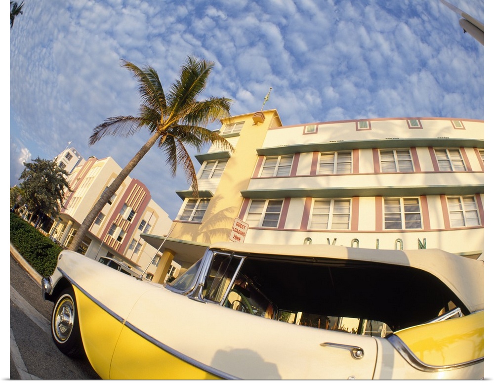 A vintage style car is pictured while parked in front of a Miami building from a low angle view.