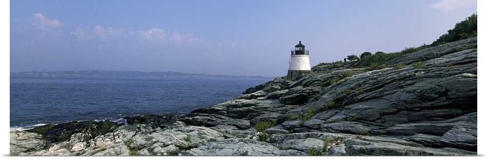 A small lighthouse sits on the edge of rocky terrain and overlooks the Atlantic ocean.