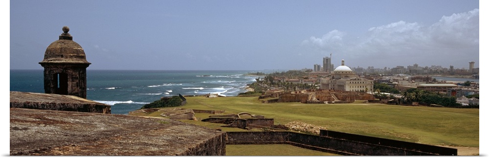 The coast of San Juan is photographed in panoramic view with the ocean to the left and the city on the right.