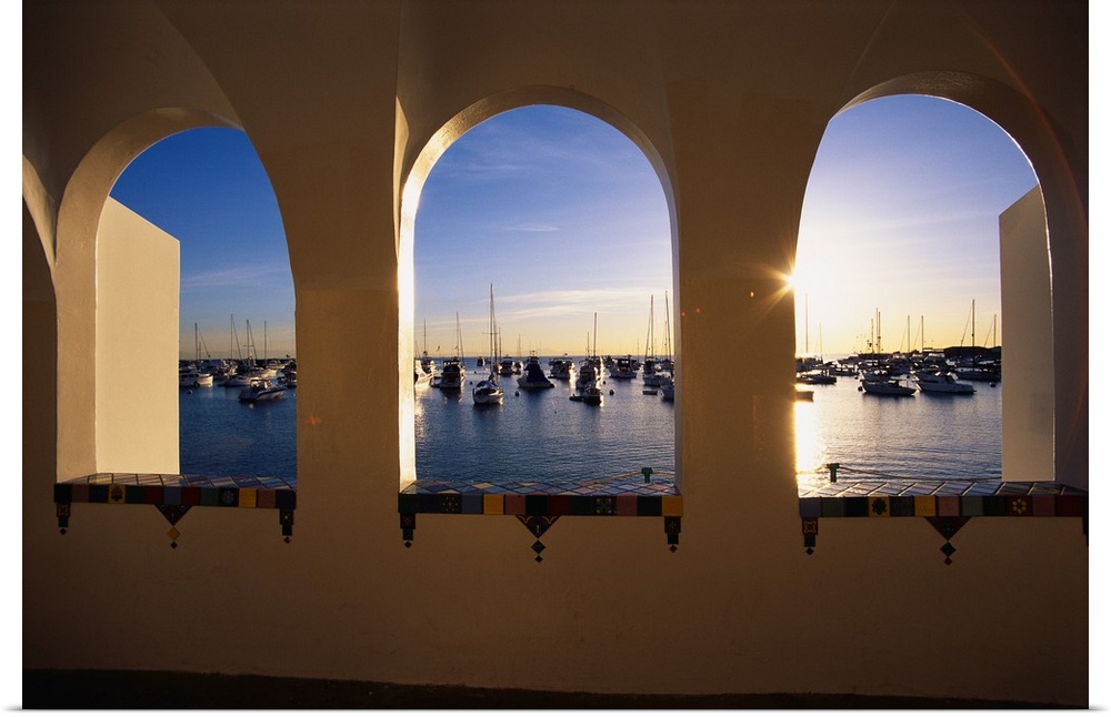 Big, landscape photograph looking through three windows at the Catalina Casino, numerous boats sitting in the water of the...