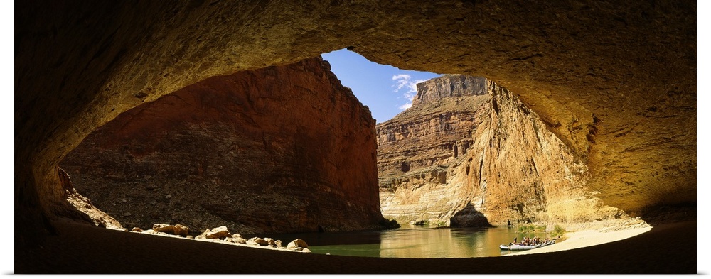 Wide angle photograph, looking out of a large cave opening near the Colorado River in Arizona.  Large sandstone formations...