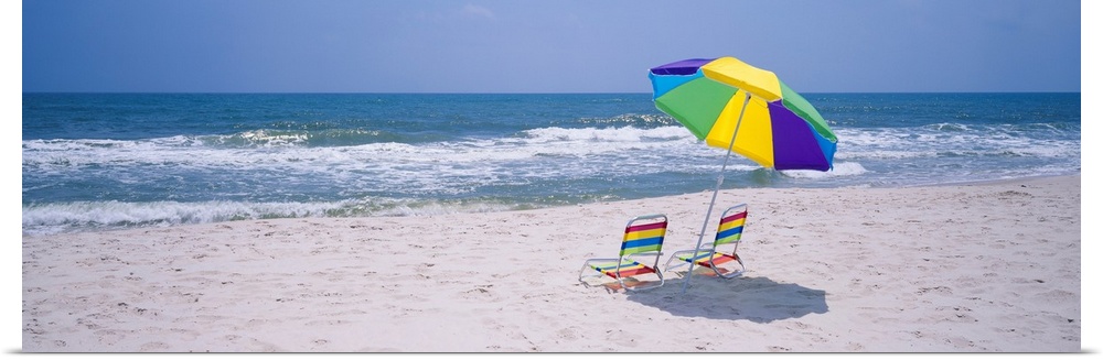 Panoramic photograph includes two chairs sitting under a vibrantly colored umbrella as the waves from the Gulf of Mexico h...