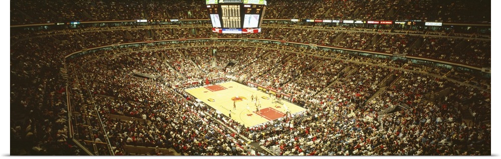 A large panoramic photograph taken inside the Chicago Bulls stadium. The seats are filled with fans as they watch the game.