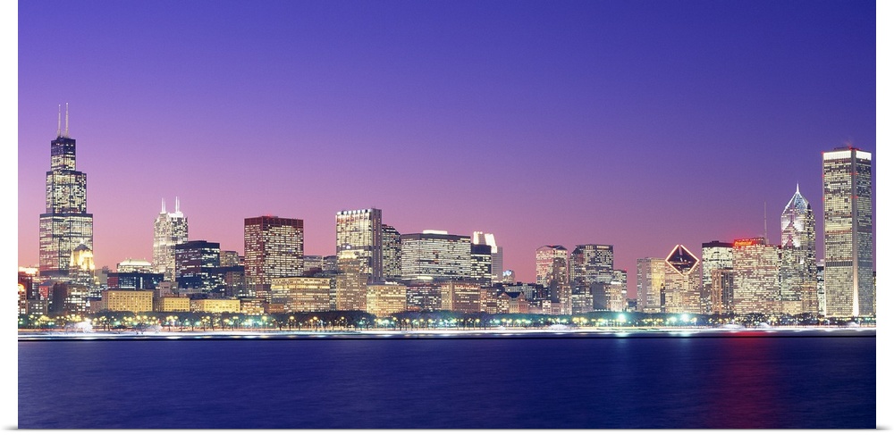 Large photo on canvas of a lit up cityscape by the waterfront at dusk.