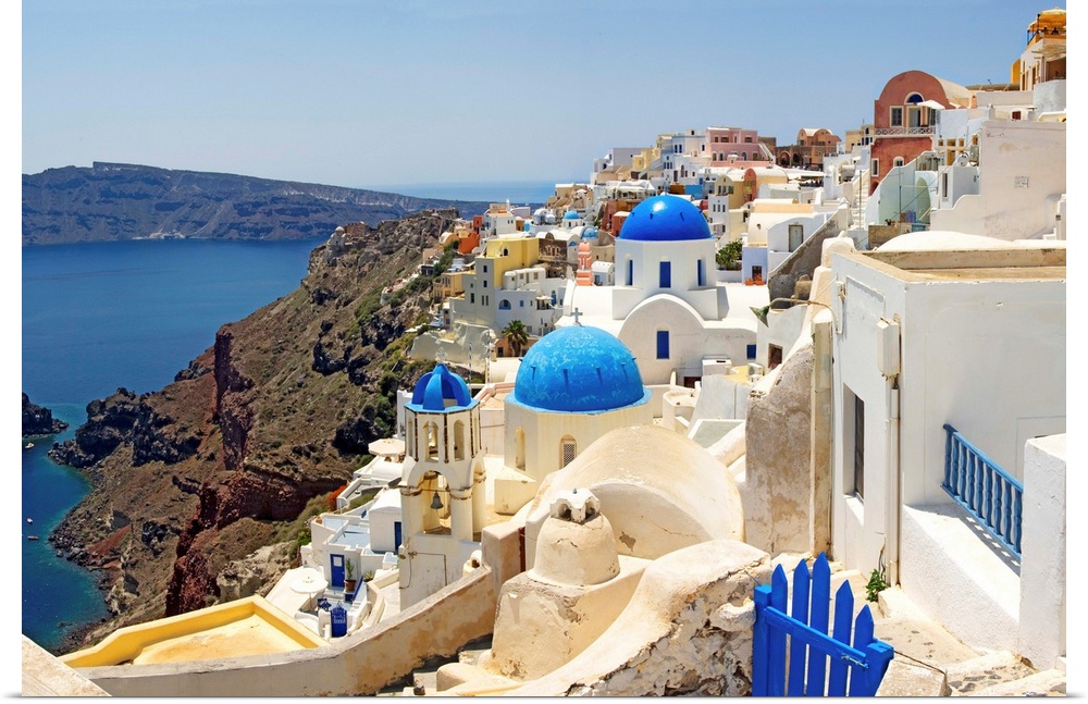 This hillside city with its famous colored roof tops overlooks a rocky Grecian sea in this panoramic photograph.