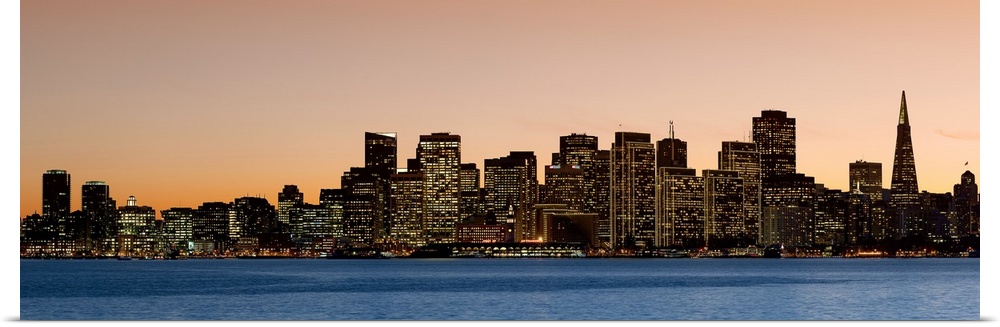 Horizontal image on canvas of the San Francisco skyline lit up at sunset by the water.