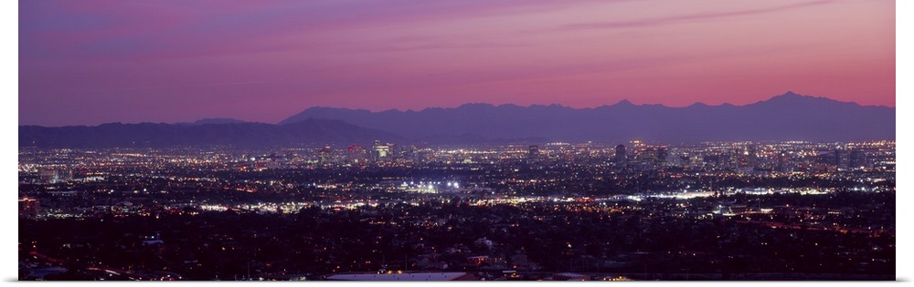 The city of Phoenix is illuminated under a dusk sky and shot in a panoramic view to show majority of the city.