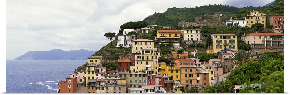 This panoramic landscape photograph of homes built into the hillside overlooking the sea.