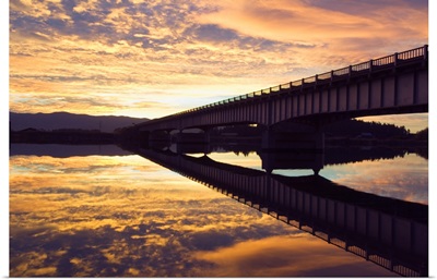 Cloudy sunset sky over bridge, reflection in Flathead River, Montana